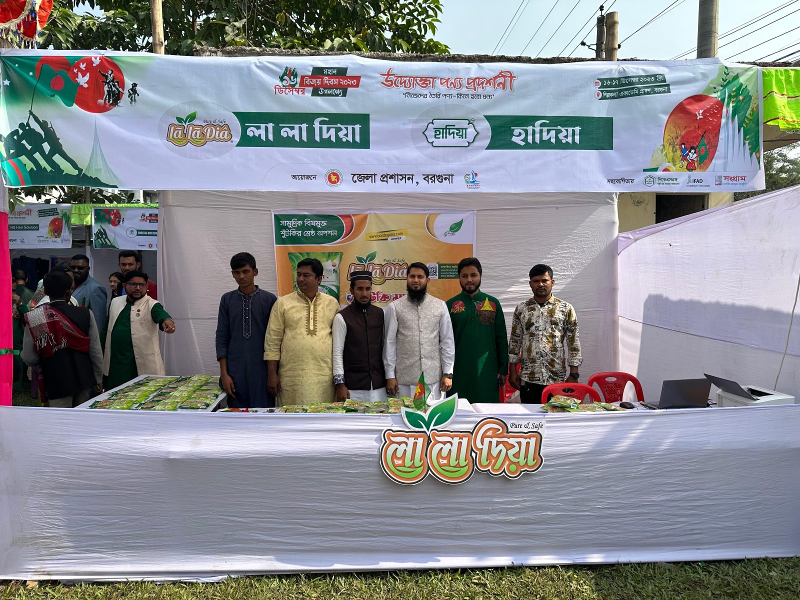 লা লা দিয়ার স্টল, টেবিলে সাজানো শুঁটকি মাছের প্যাকেট, উপরে প্রদর্শনীর ব্যানার